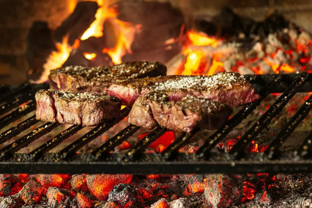How Do You Use a Smoker BBQ? A Practical Guide to Getting Started 2 Steaks cooking over hot charcoal on a BBQ grill.