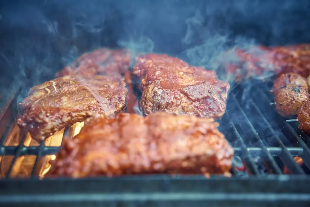 How Do You Use a Smoker BBQ? A Practical Guide to Getting Started 1 Meat cooking low and slow inside a smoker BBQ with visible smoke.