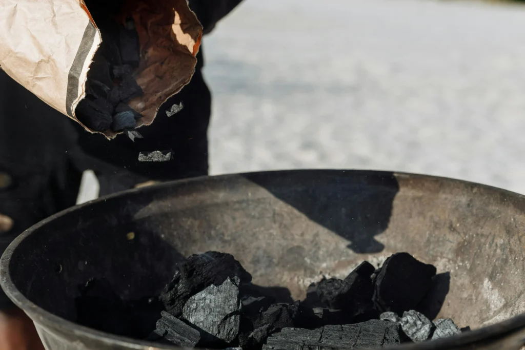 What Is a Wood-Fired BBQ and Is It Worth It? 1 Lumpwood charcoal being poured from a bag into a kettle BBQ, ready for lighting.